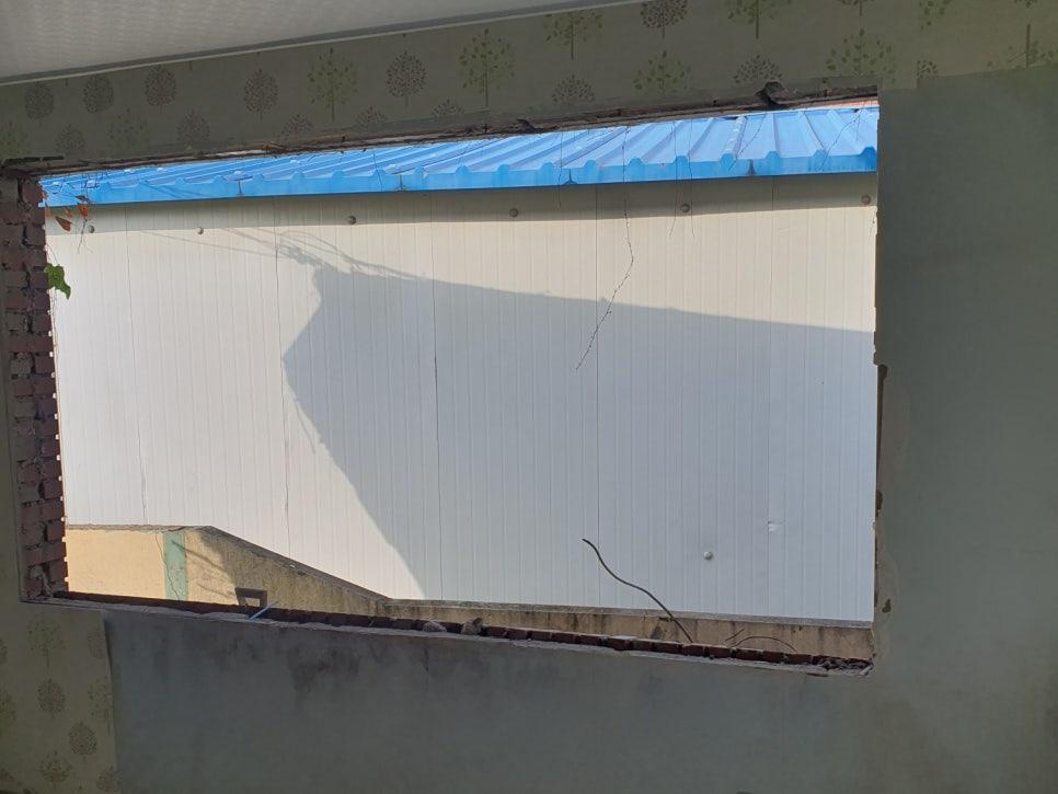 흰색 금속 구조물과 파란색 지붕재가 보이는 벽면