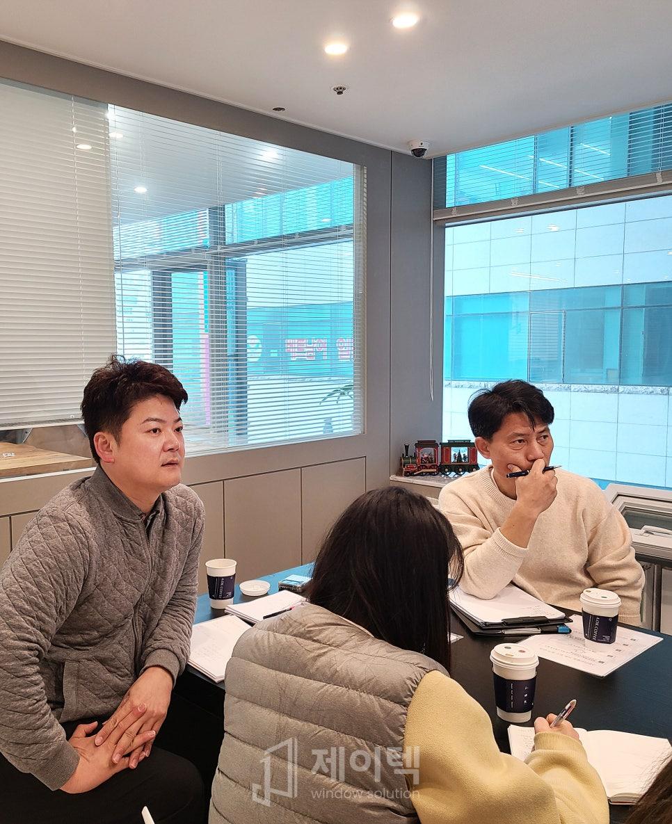회색 벽면의 공간에서 메모하며 논의하는 장면