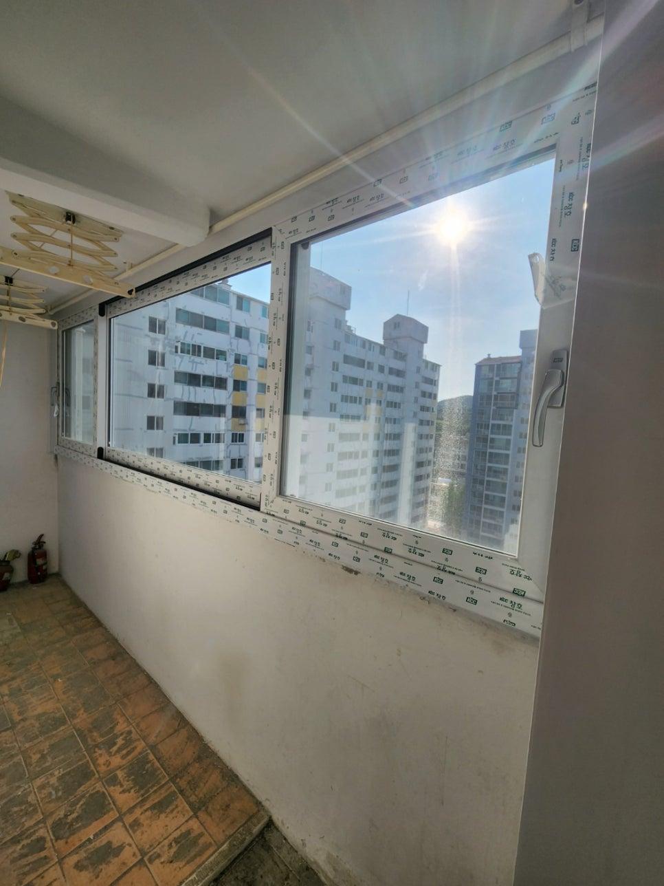 갈색 타일 바닥과 흰색 프레임 창호가 설치된 발코니