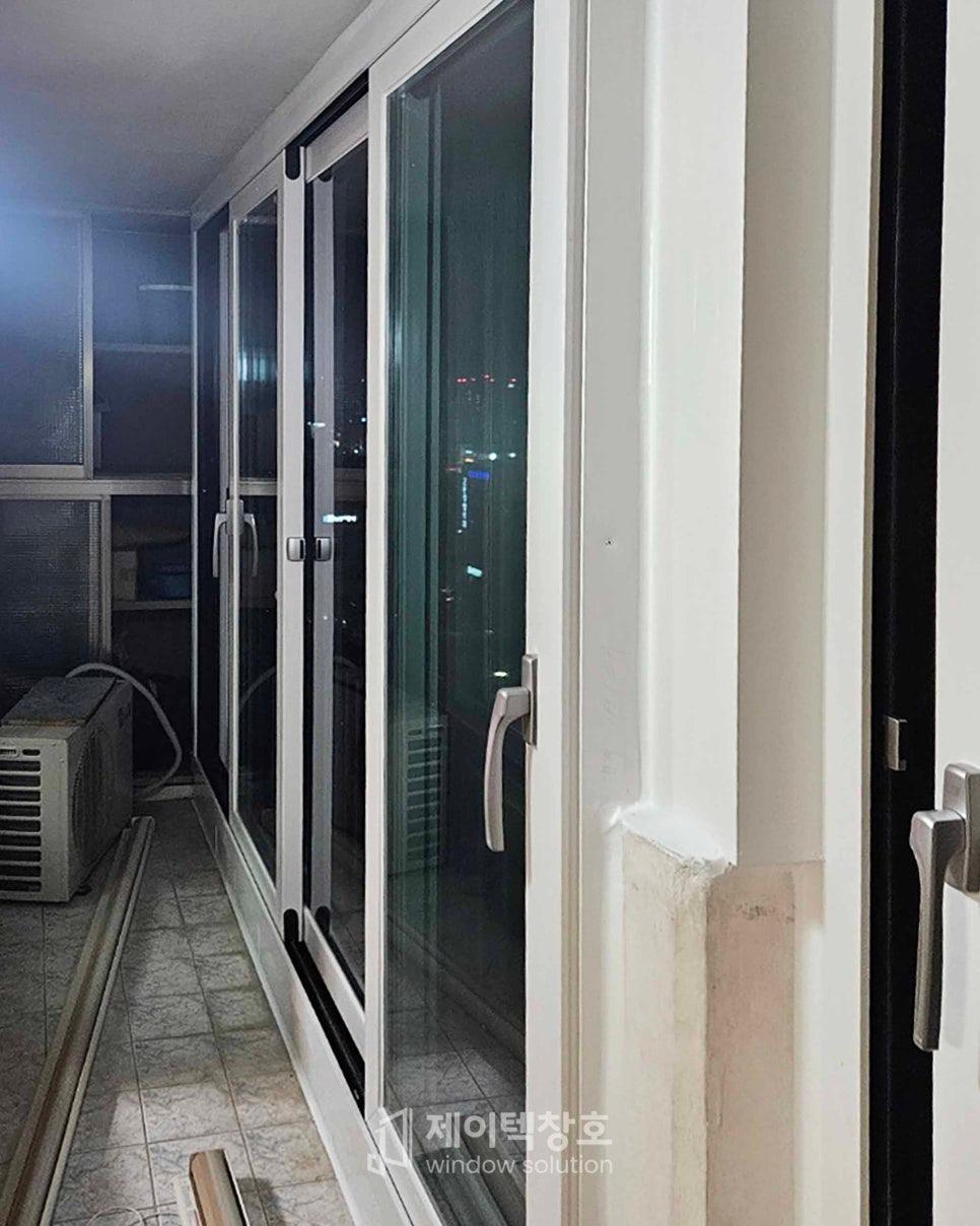 흰색 프레임의 슬라이딩 창호와 도시 야경 반사