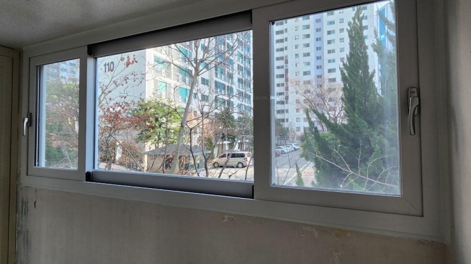 회색 프레임 창호 너머로 보이는 고층 아파트 전경