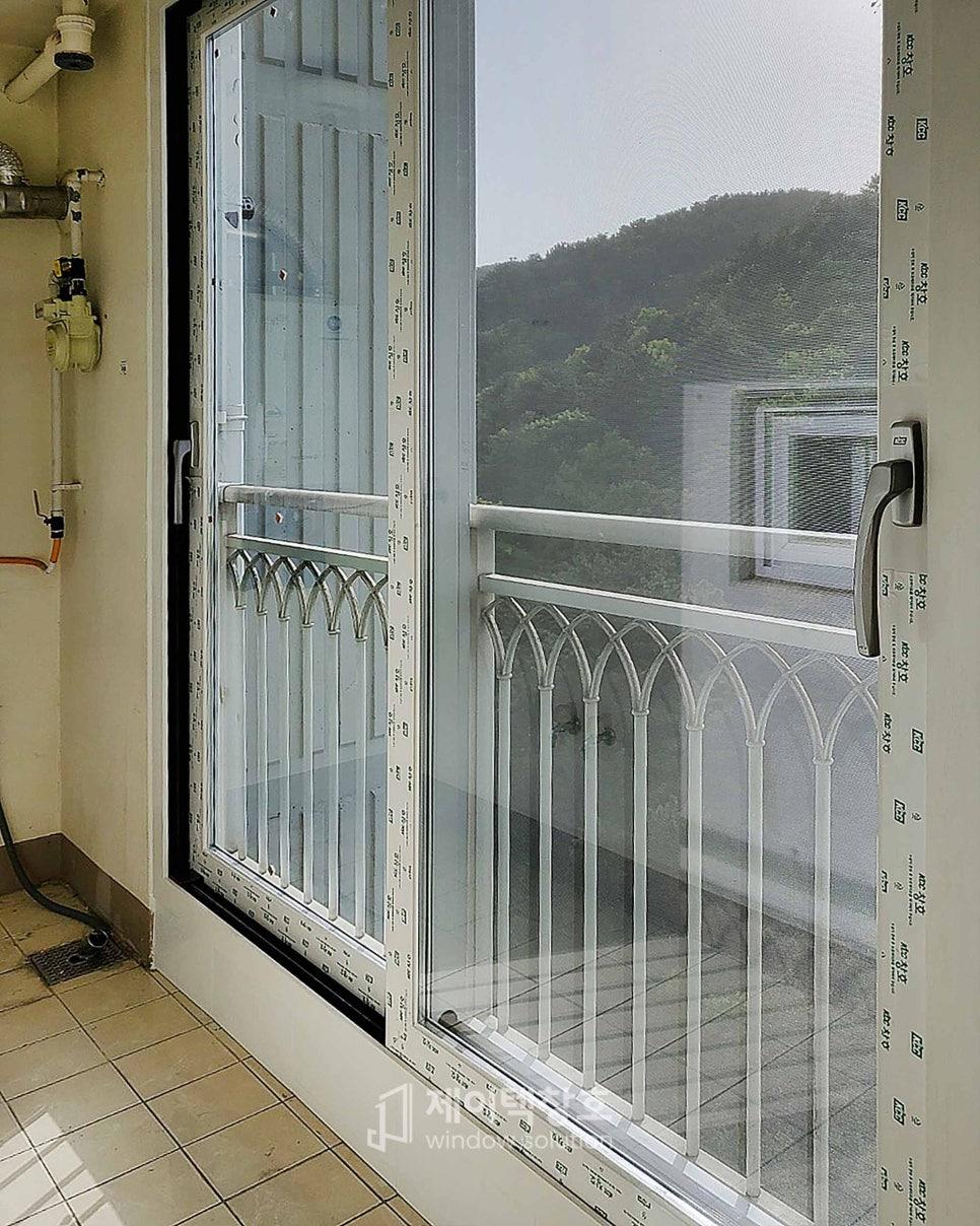 흰색 금속 울타리 너머로 산과 건물이 보이는 창가
