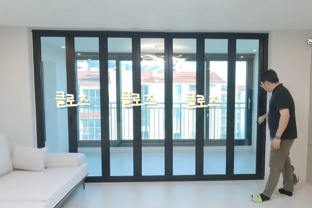 흰색 소파와 블랙 프레임 도어가 배치된 공간