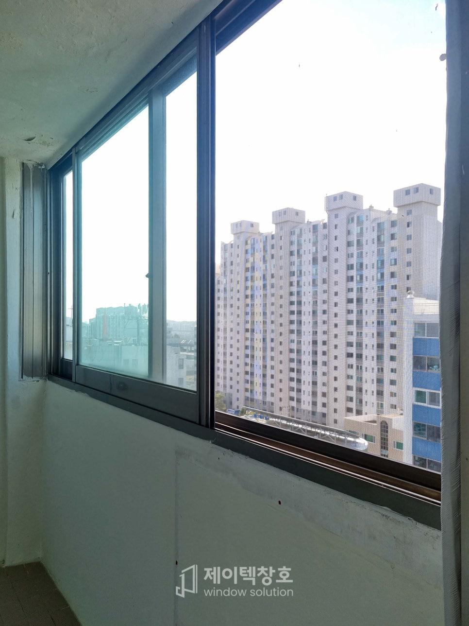 검은색 프레임이 설치된 창호와 외부 아파트 전경