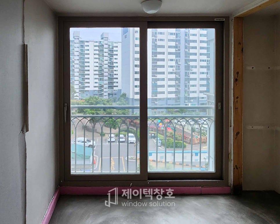 회색 타일 바닥과 외부 아파트 단지가 보이는 창호