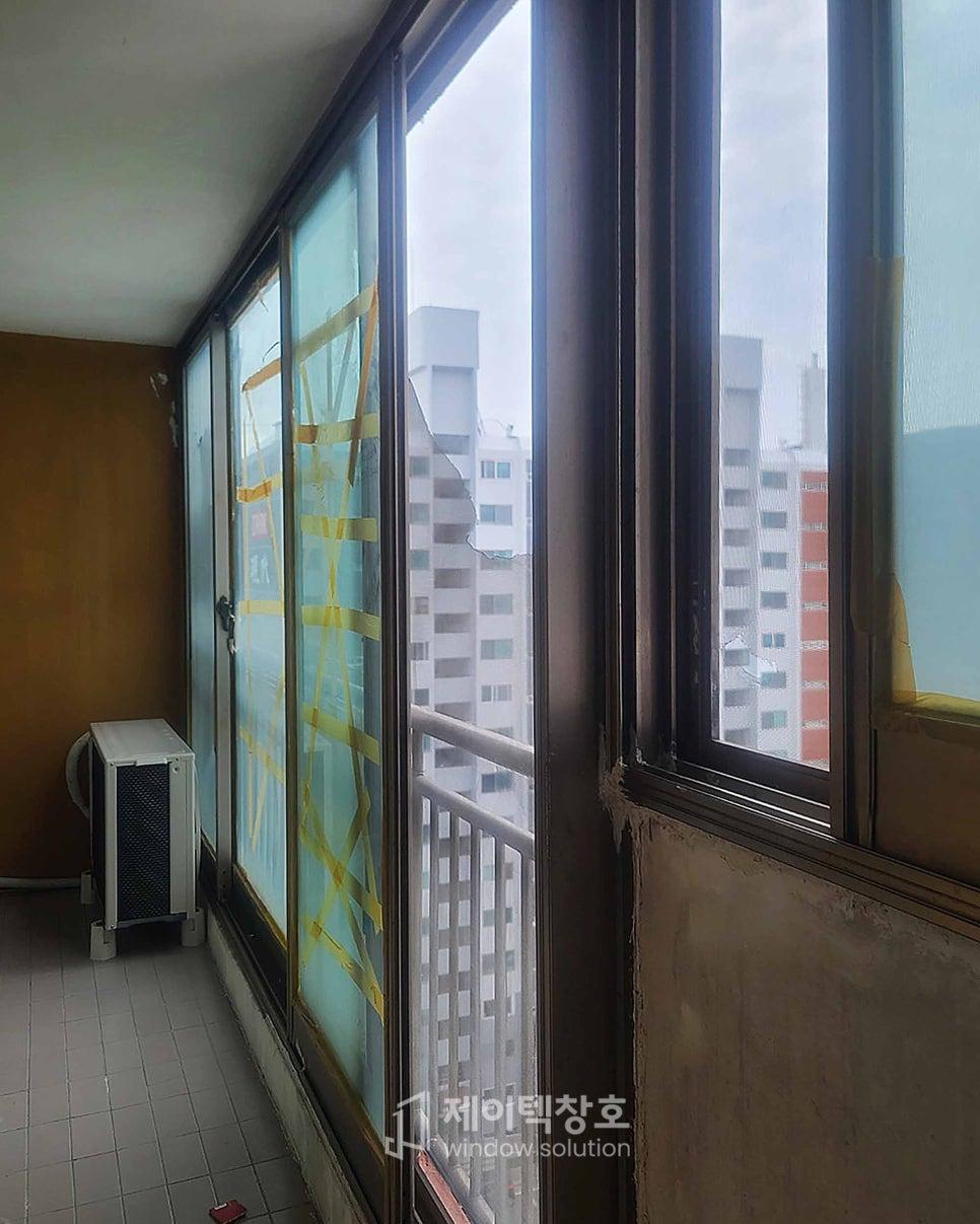 노란색 테이프가 붙은 기존 창호와 흰색 타일 바닥의 발코니