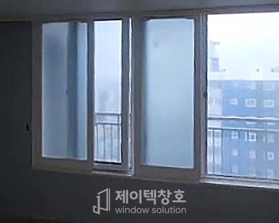 회색 프레임과 외부 건물이 흐릿하게 보이는 창호 근접 샷