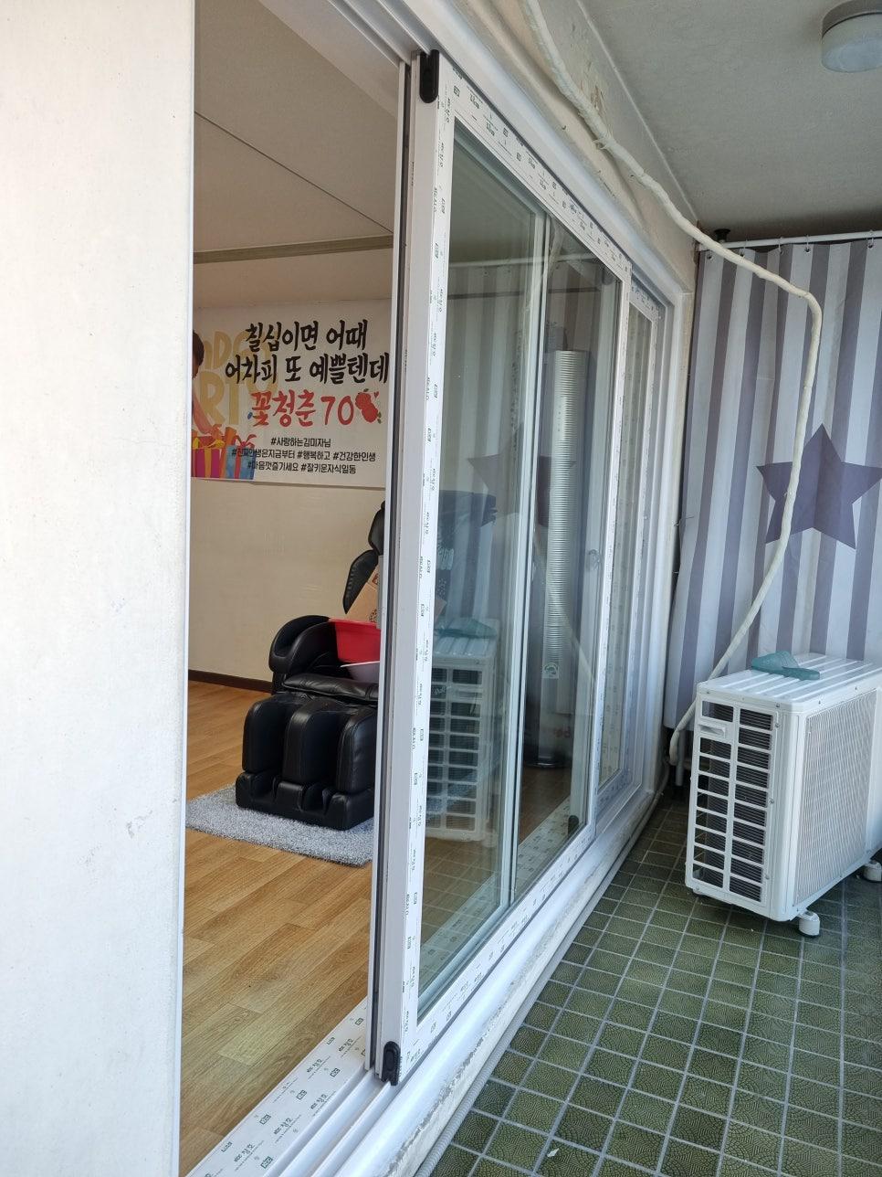 녹색 타일 바닥과 흰색 슬라이딩 도어가 설치된 발코니