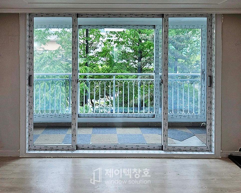 목재 마루가 깔린 실내와 발코니를 연결하는 슬라이딩 유리문