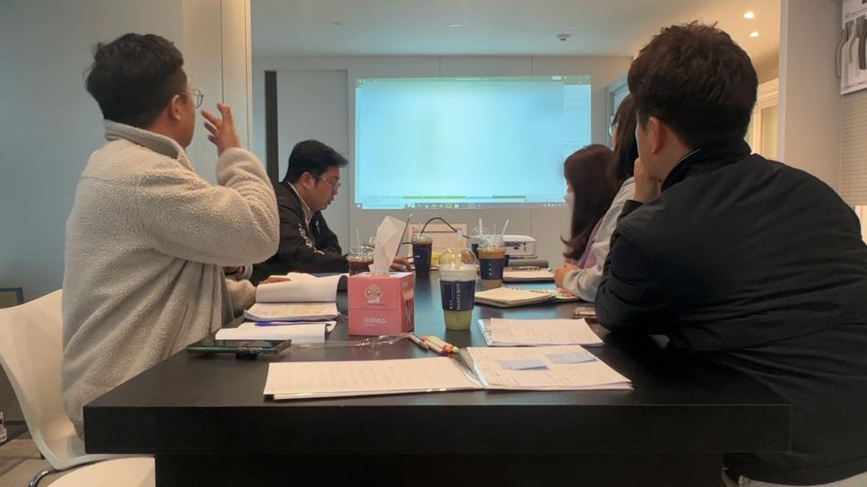 프로젝터 화면과 테이블이 보이는 회의실 내부