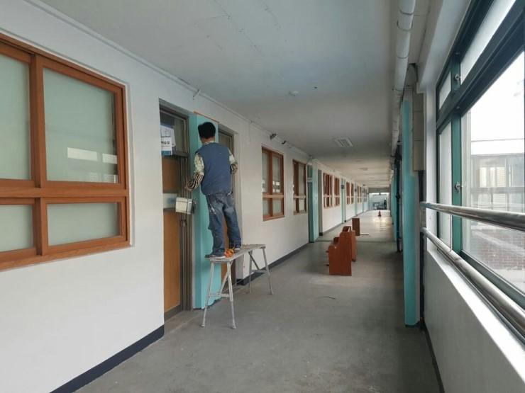 흰색 벽면과 파란색 문틀이 맞닿은 복도 창가
