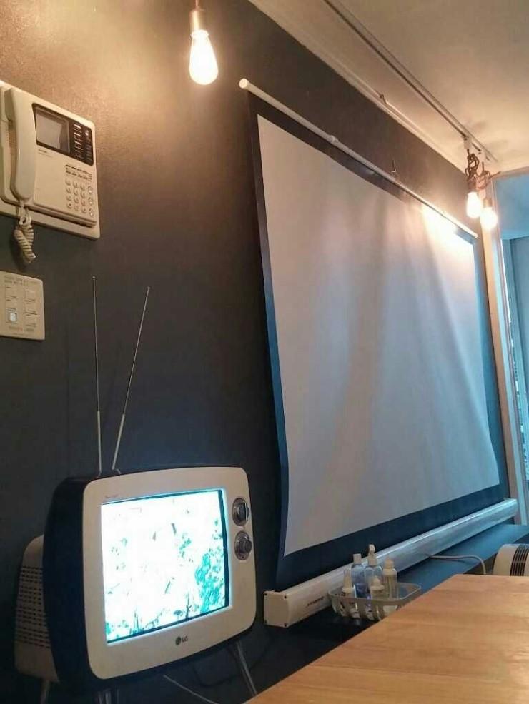 스크린과 TV가 설치된 어두운 톤의 실내 공간