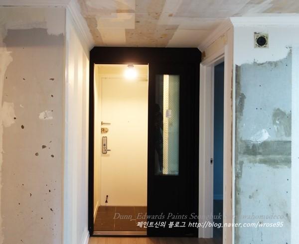 흰색 페인트 마감이 진행 중인 복도와 현관 연결부