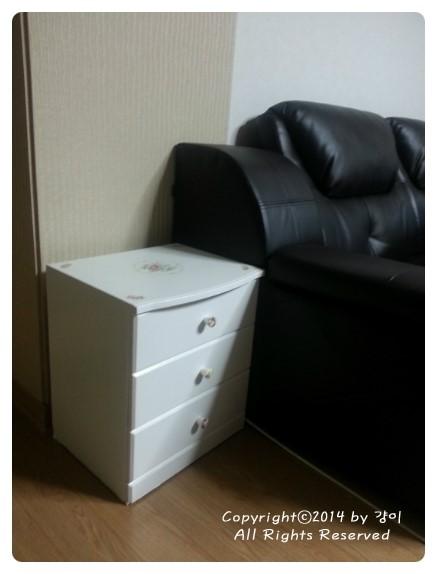 검은색 가죽 소파 옆에 배치된 화이트 수납장