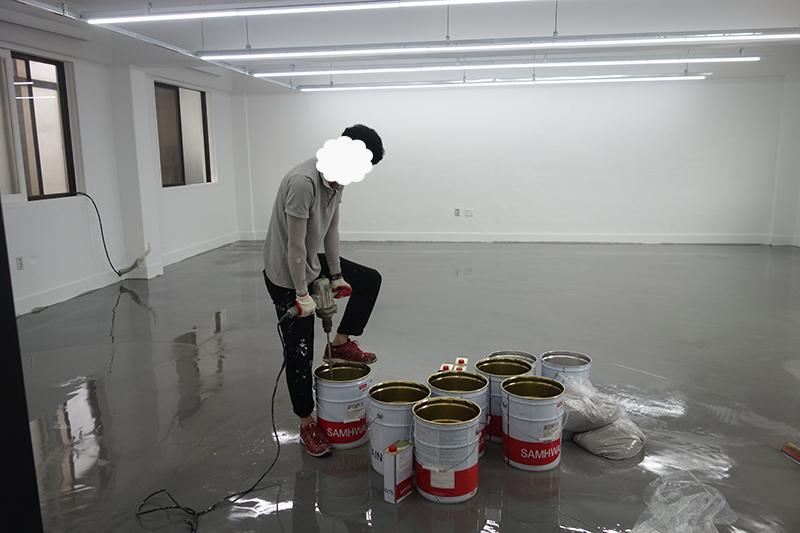광택 바닥 위에 놓인 페인트 통과 작업 현장