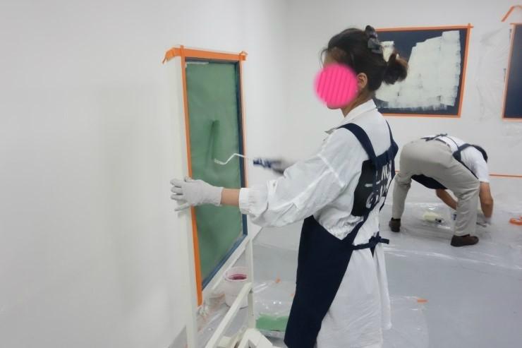 보양재가 깔린 벽면에 페인트를 칠하는 작업자