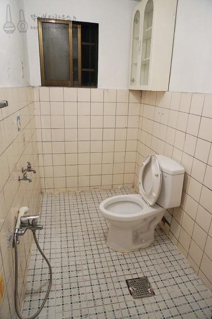 양변기와 샤워 설비가 보이는 욕실 벽 타일 장면