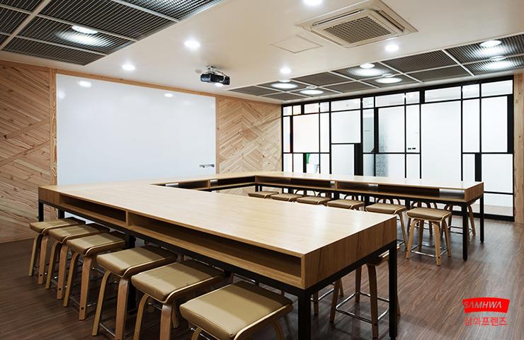 목재 벽면과 스크린이 설치된 교육 공간