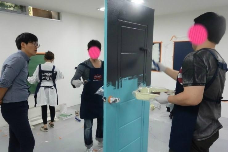 흰색 벽과 대비되는 파란색 문 도장 작업