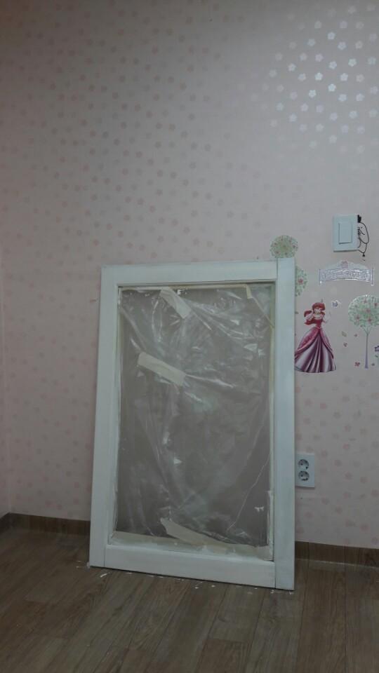 분홍색 점무늬 벽지와 보양 필름이 덮인 문 프레임