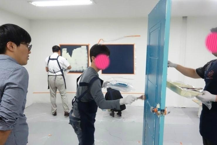 바닥 보호 필름 위에서 파란색 도어를 작업하는 현장