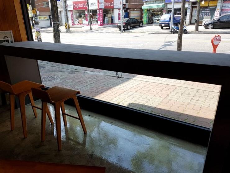 나무 의자와 어두운 카운터가 배치된 창가 공간