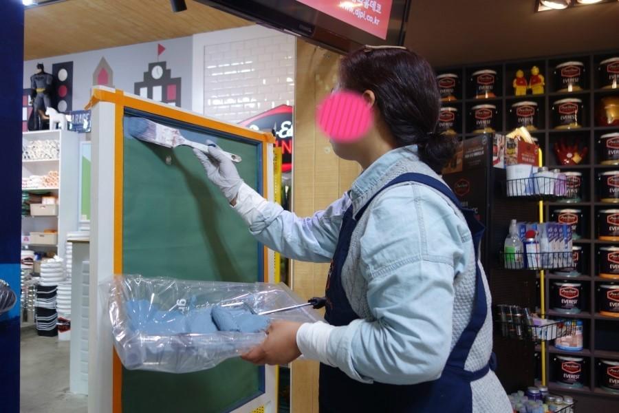 녹색 페인트로 벽면을 칠하는 작업 모습