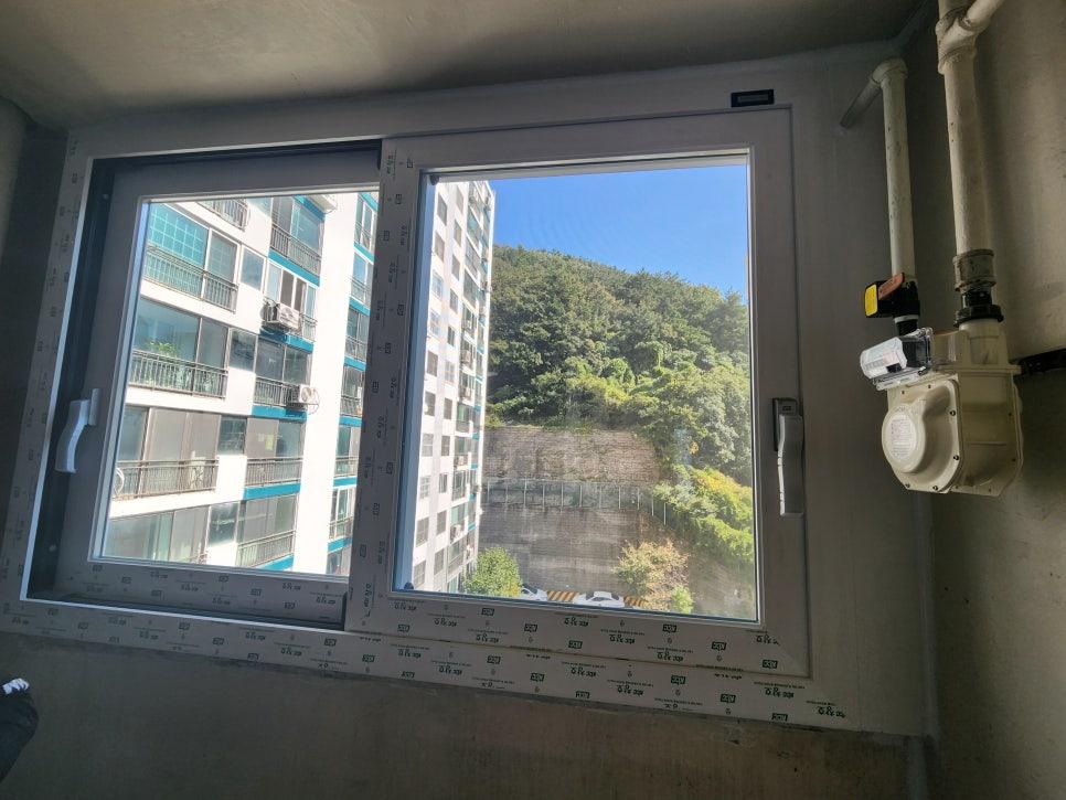 외부 건물과 산이 보이는 열린 상태의 창호 프레임 근접 샷