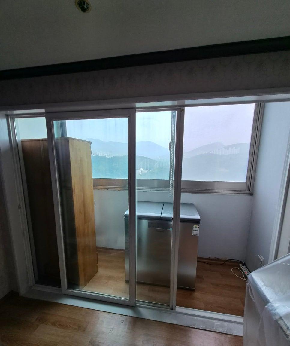 산과 건물이 보이는 슬라이딩 창호와 내부 가구 배치