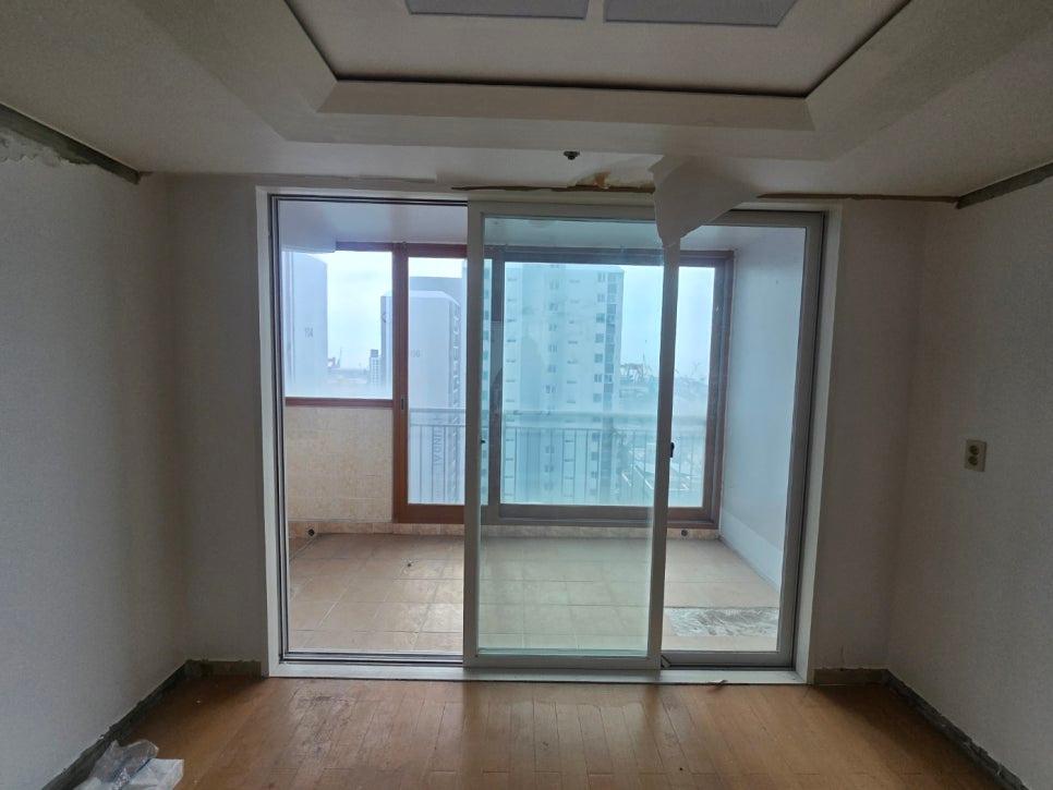 목재 바닥과 흰 벽면 사이 설치 중인 유리 도어