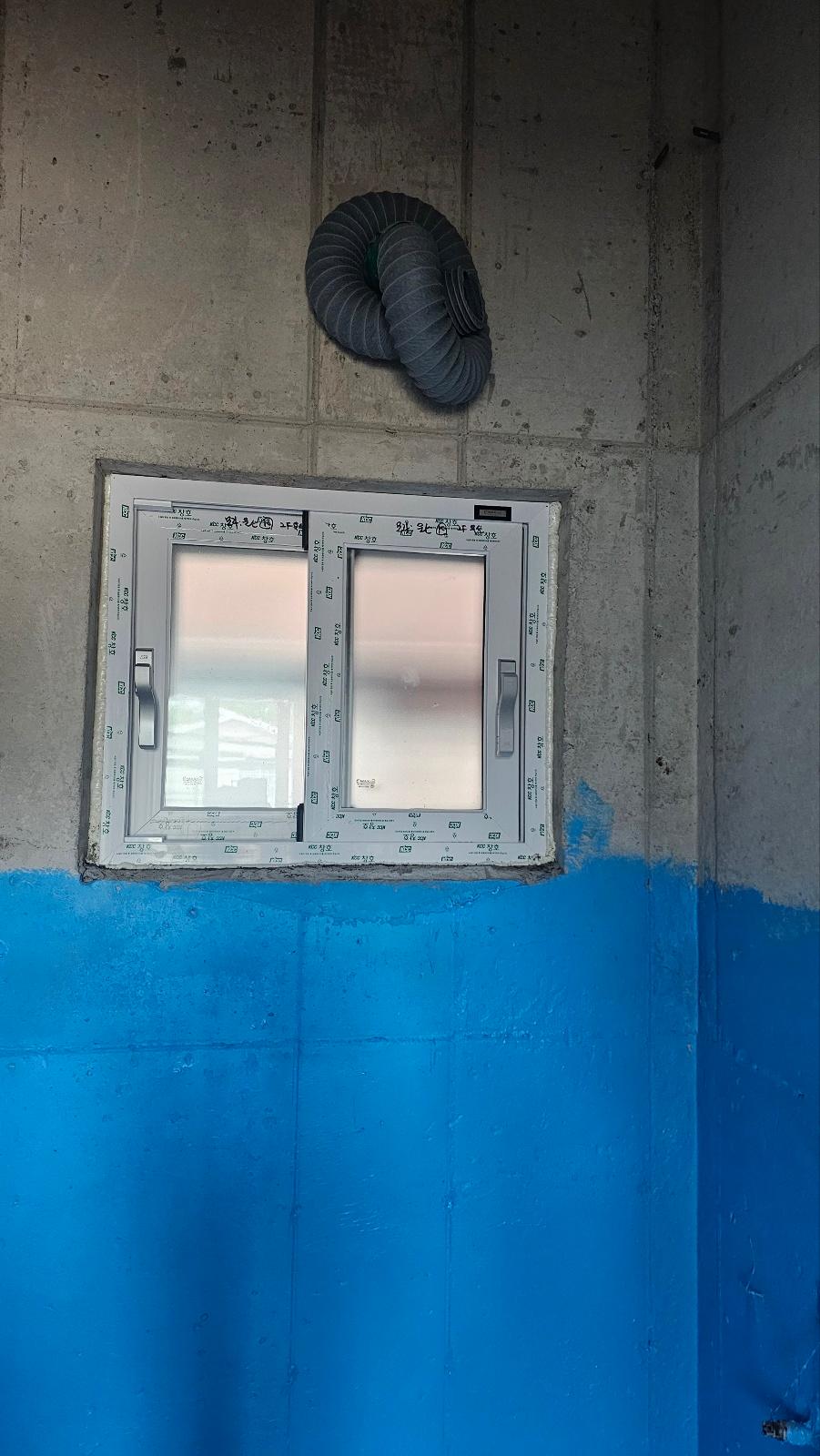 콘크리트 벽면에 설치된 창호와 상부 배관
