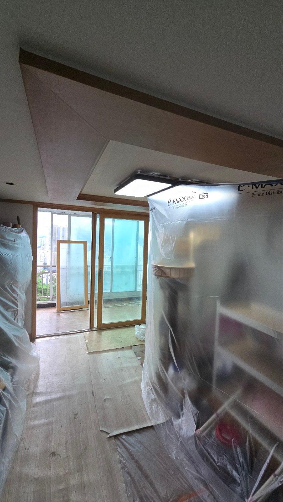 보호재로 덮인 가구와 설치 중인 유리문