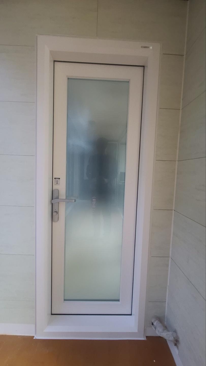 흰색 도어와 타일 벽면이 보이는 현관 공간