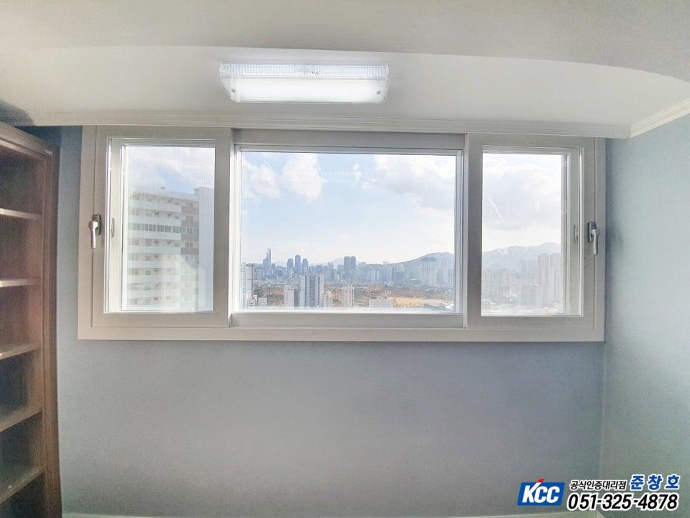 도시 전경이 내려다보이는 큰 창과 원목 선반, 천장 조명이 정갈하게 배치된 서재 공간이에요.