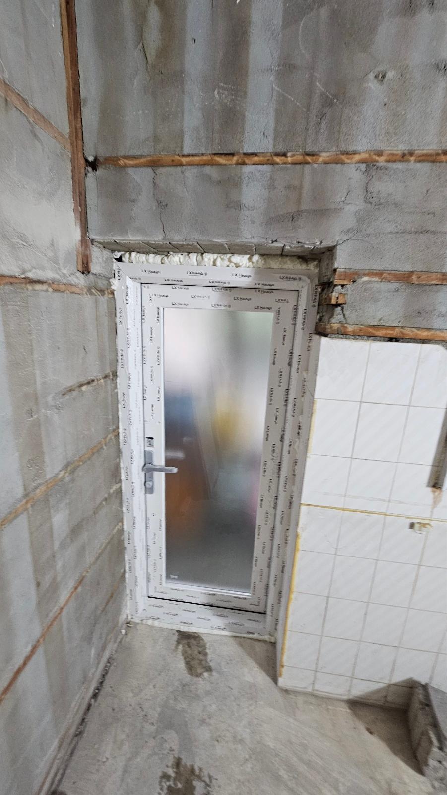 타일 벽면에 설치된 도어 프레임과 유리 패널
