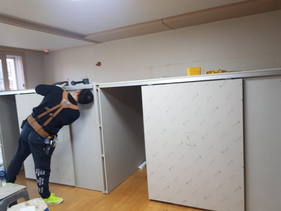 벽면에 흰색 보드를 설치하고 있는 작업 과정