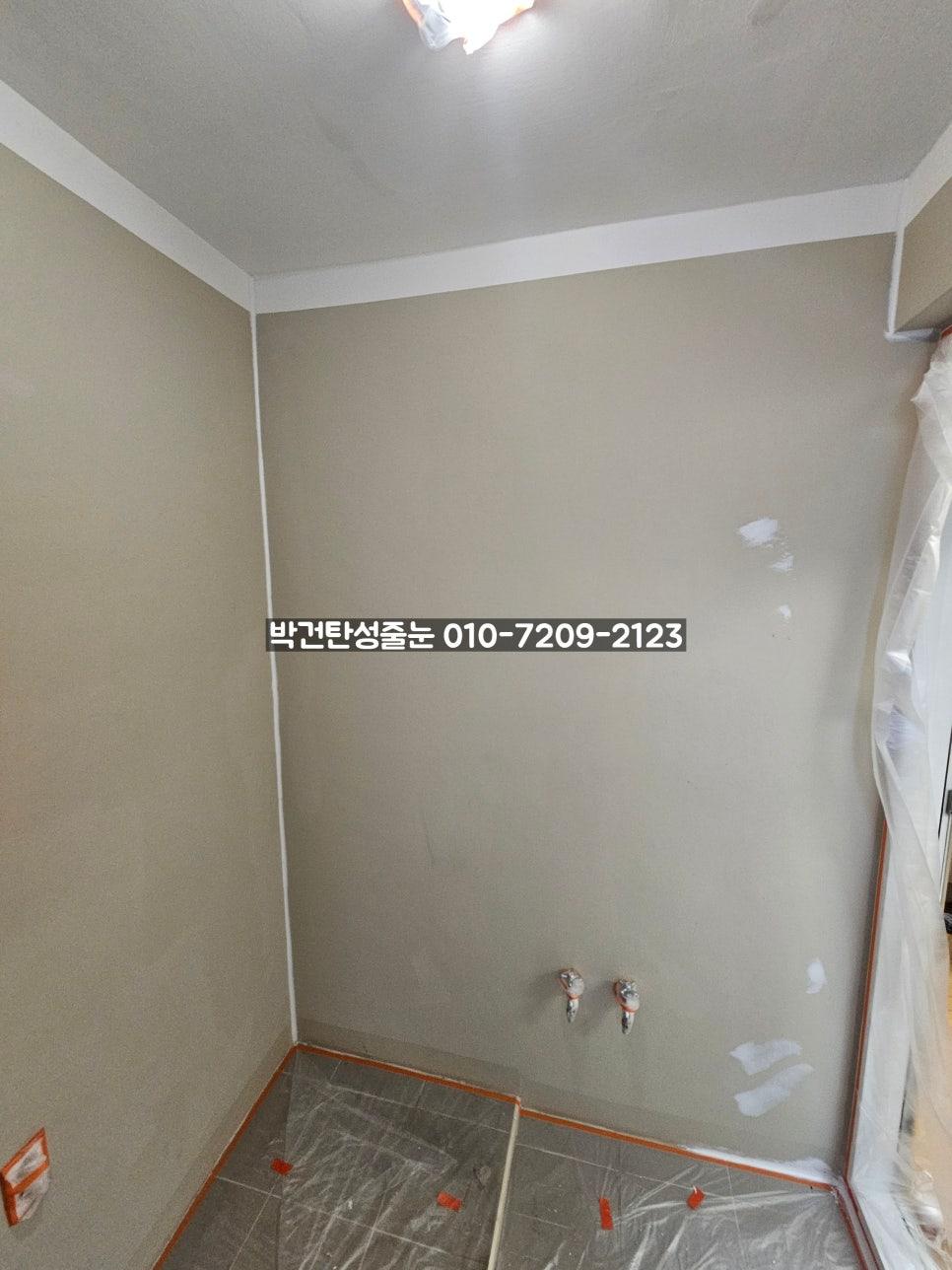 베이지색 벽면과 회색 타일 바닥에 주황색 테이프로 보양한 상태