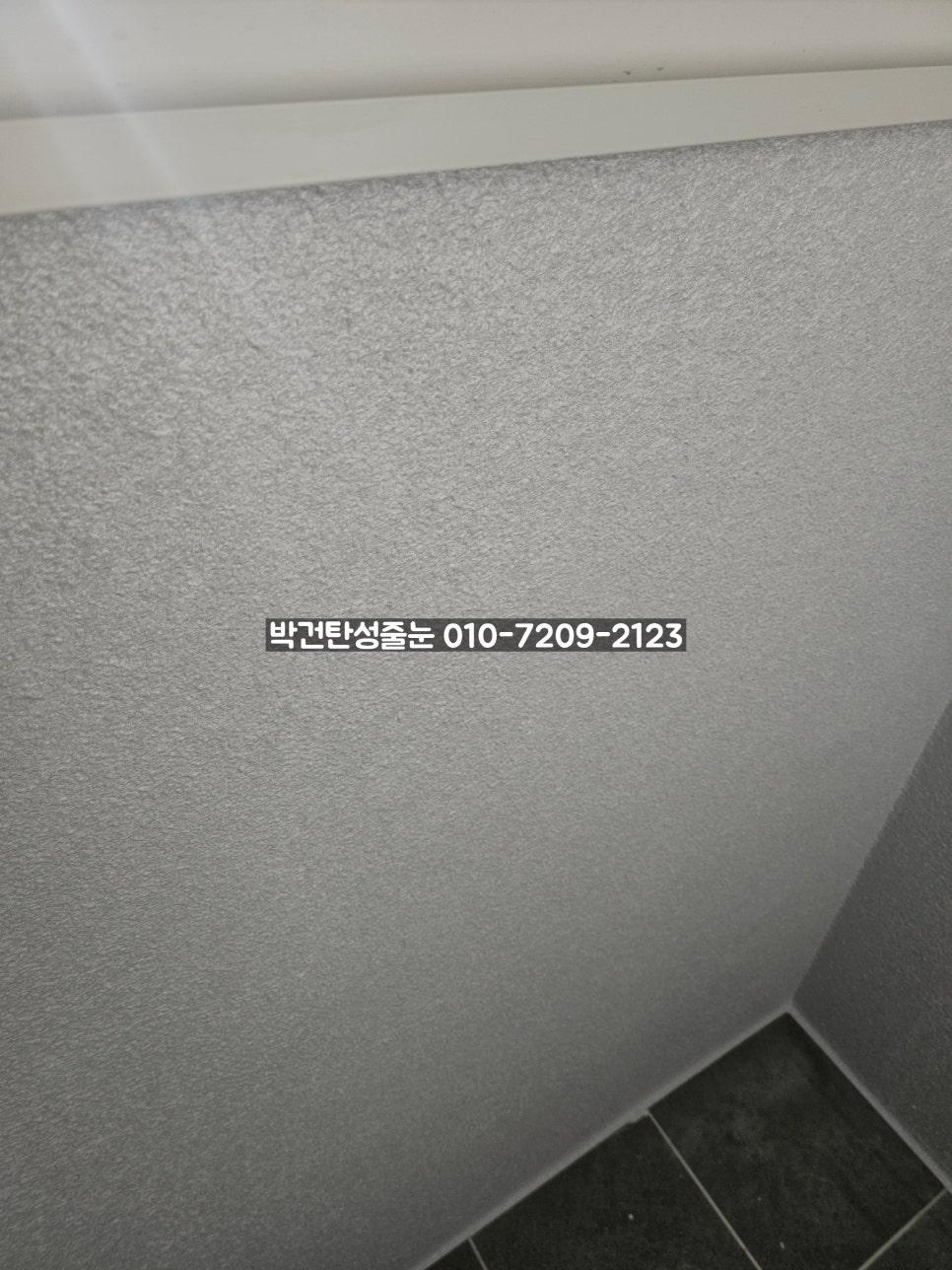 회색 텍스처 벽면과 검은 타일 바닥의 접합부