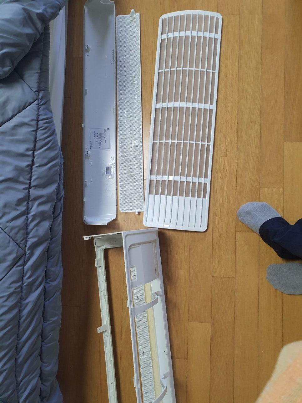 나무 바닥 위에 분리되어 펼쳐진 흰색 플라스틱 부품들