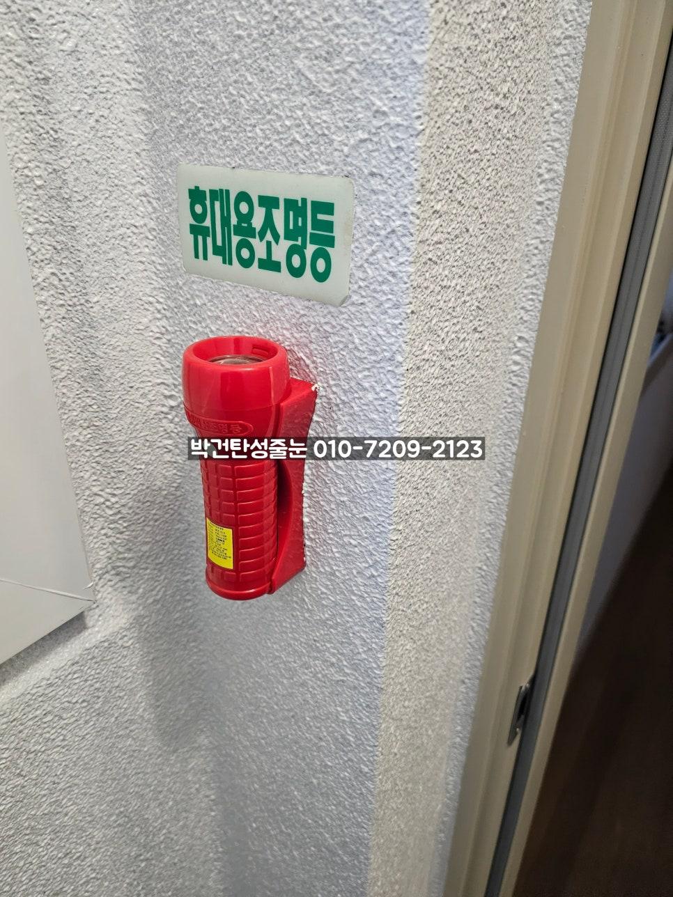 소화기와 휴대용 조명등 표지판이 부착된 흰색 텍스처 벽면