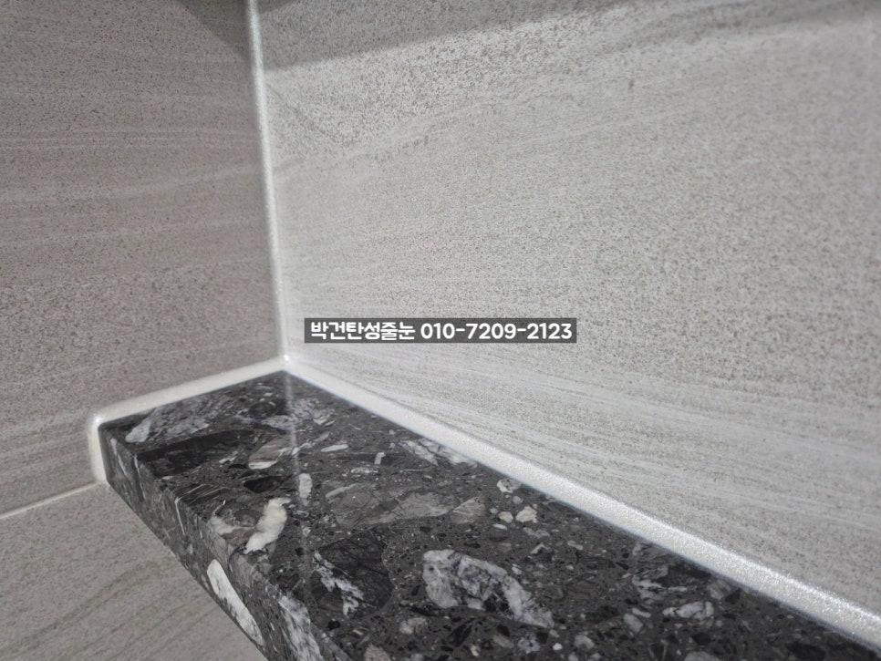 회색 타일과 무늬 있는 검은색 석재 상판의 접합부