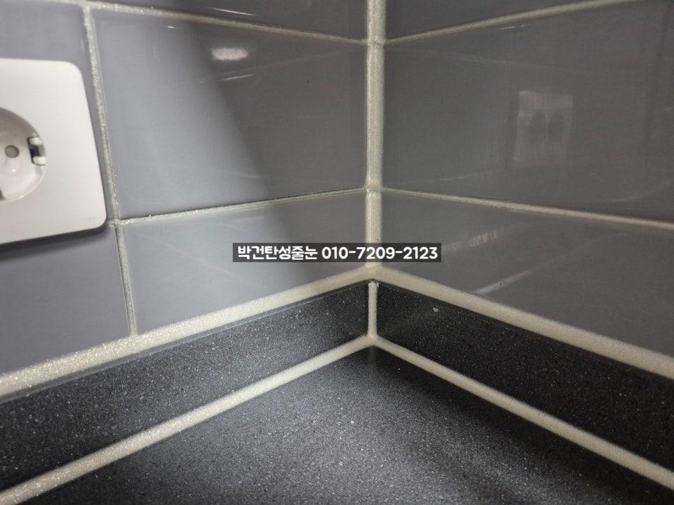 회색 타일 벽과 검은색 상판 모서리의 마감