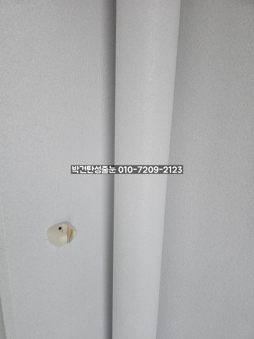 벽걸이형 스위치와 흰색 커튼이 보이는 벽면
