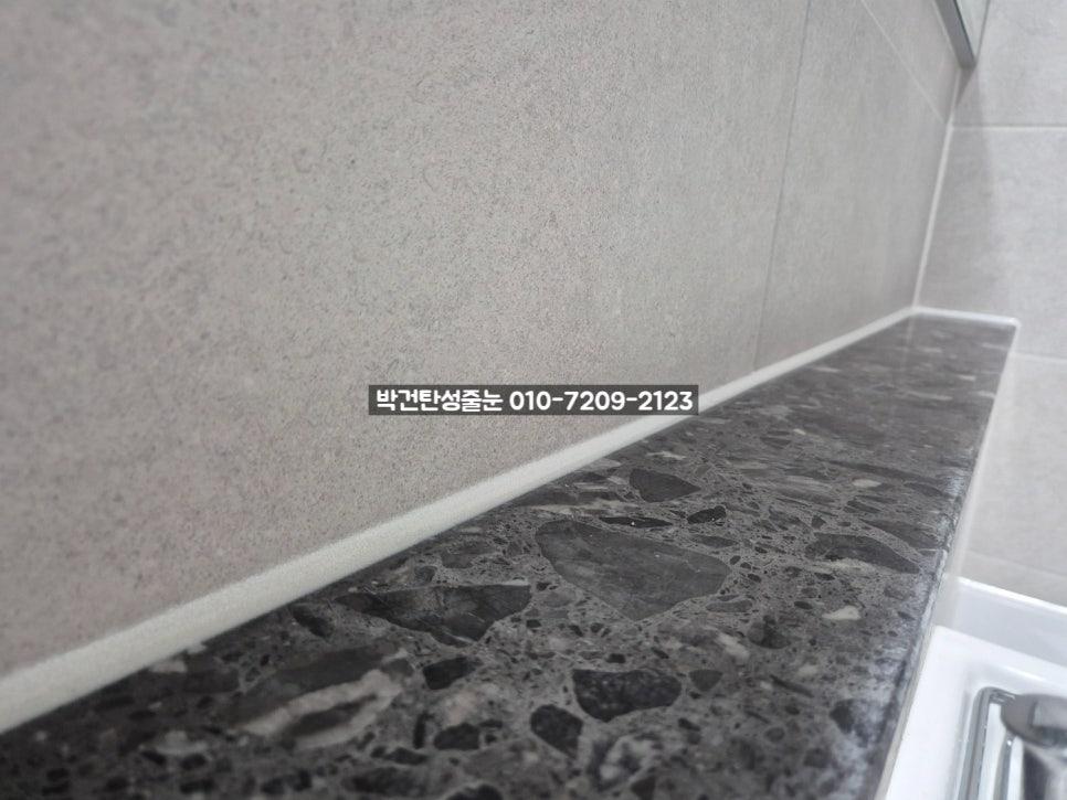 회색 타일 벽과 검은색 석재 상판의 접합부