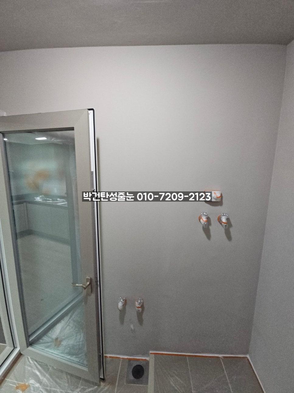 수도꼭지와 배수구가 설치된 흰 벽면의 모습