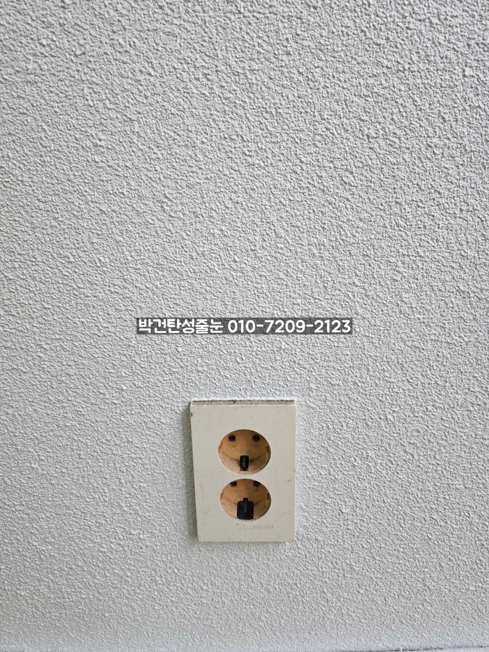 흰색 텍스처 벽면에 부착된 베이지색 전기 소켓