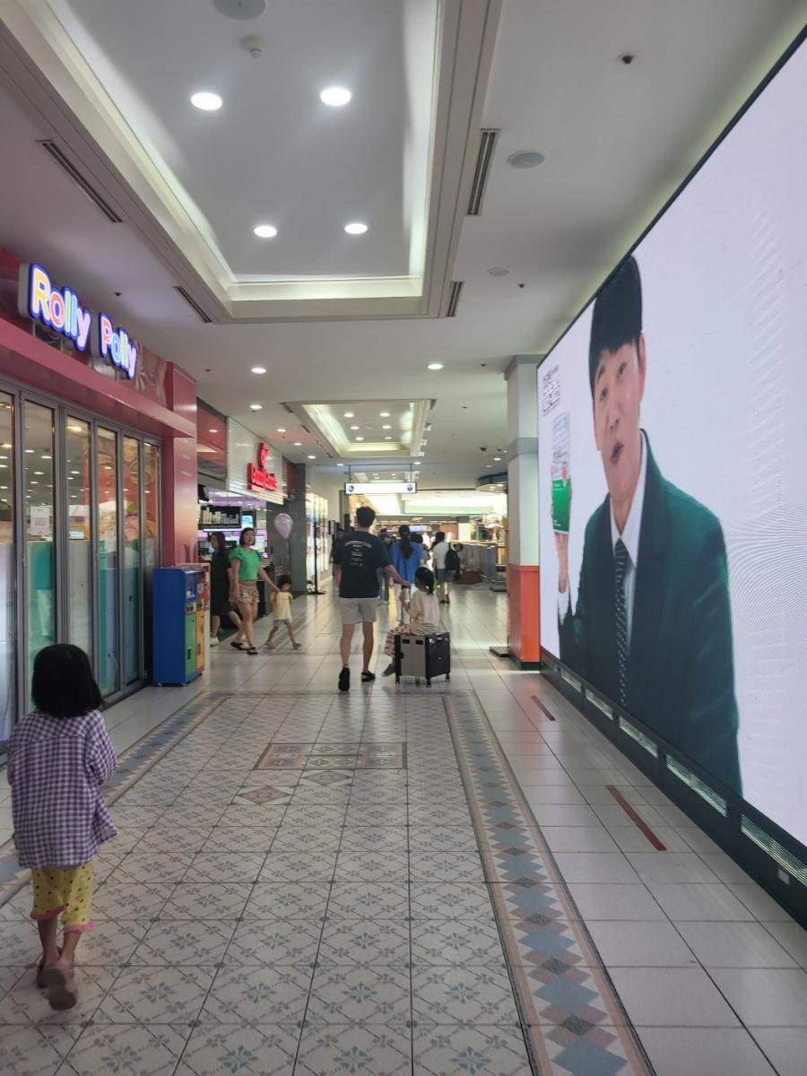 타일 마감과 대형 광고 화면이 보이는 통로