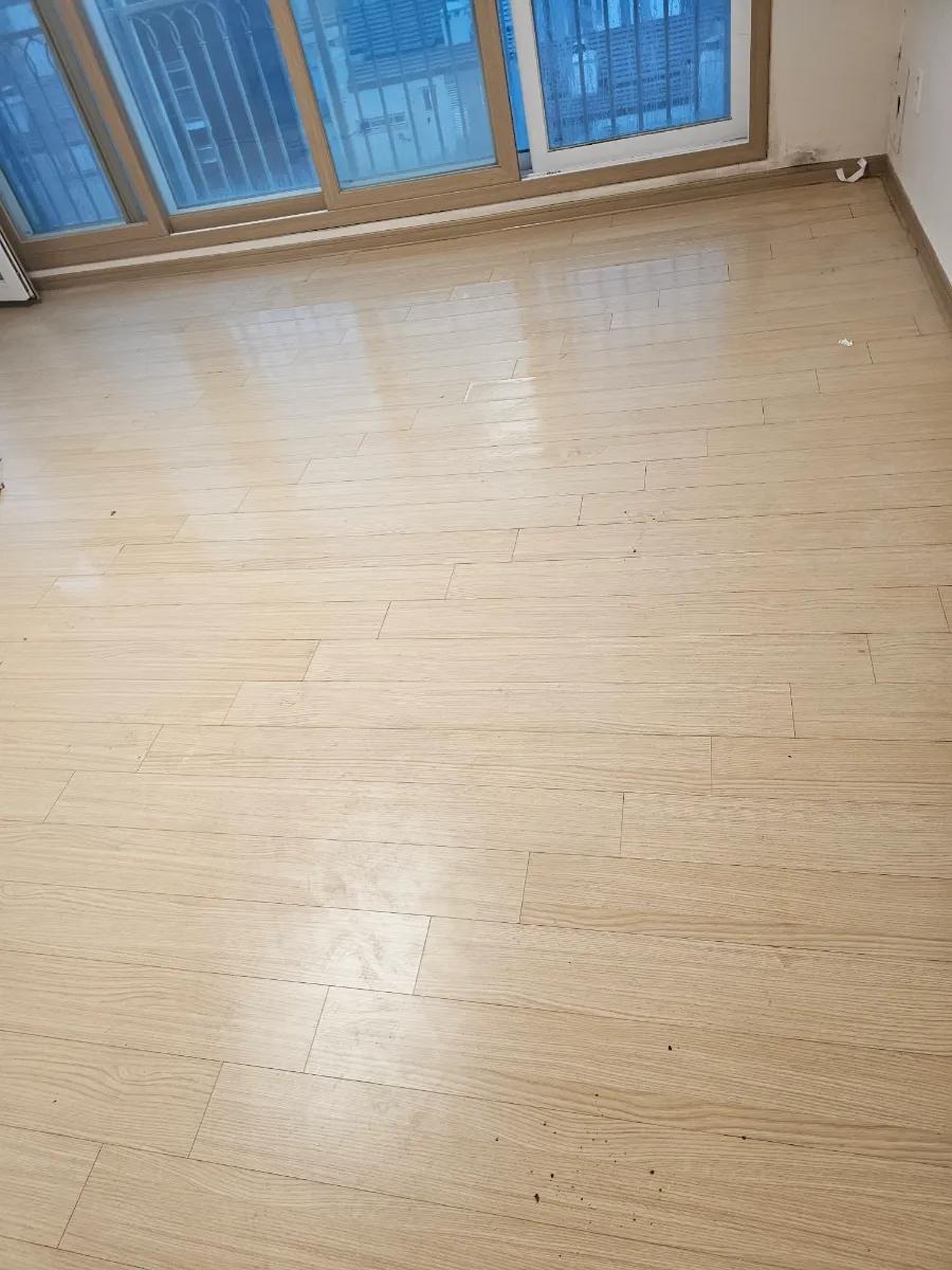 밝은 우드톤 마루가 깔린 거실 전경
