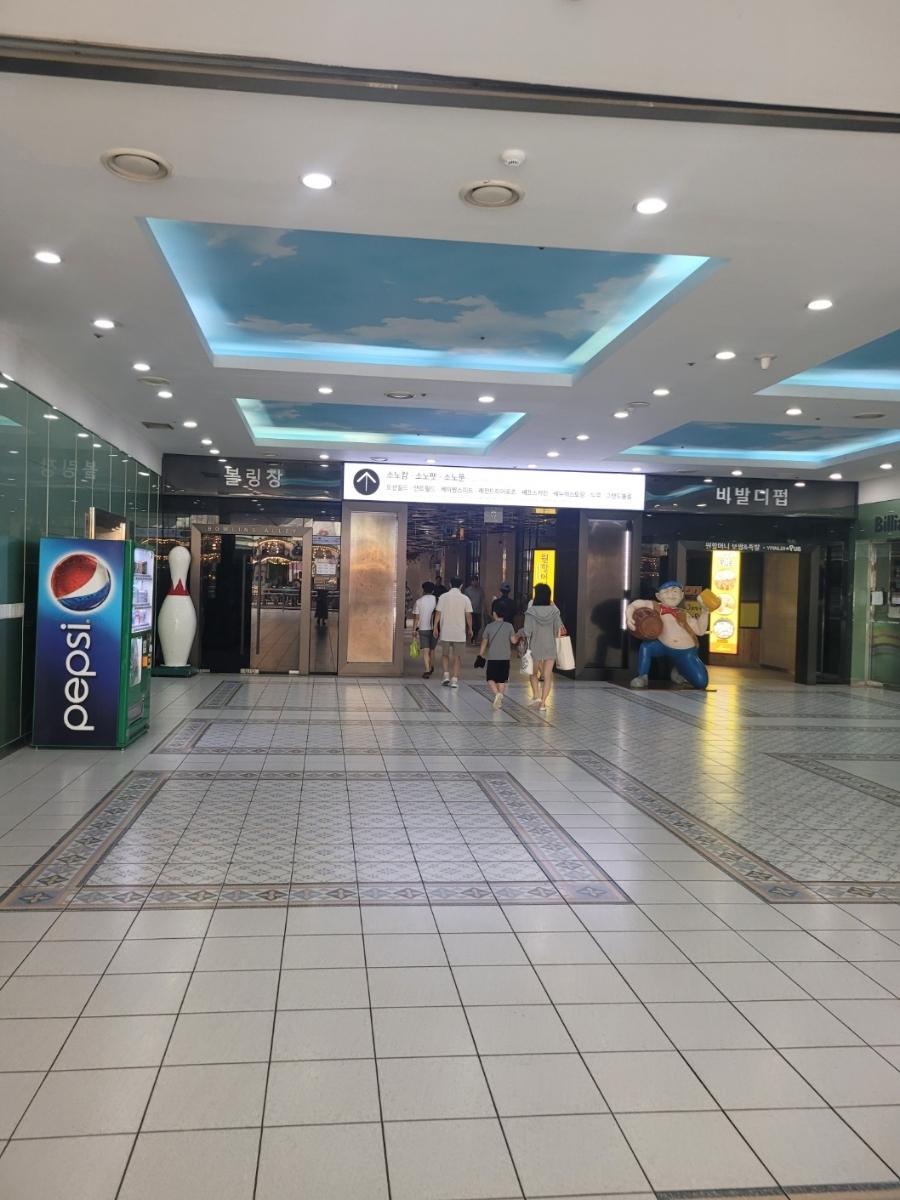 하늘 패턴 천장과 흰색 타일이 조화로운 상업 공간