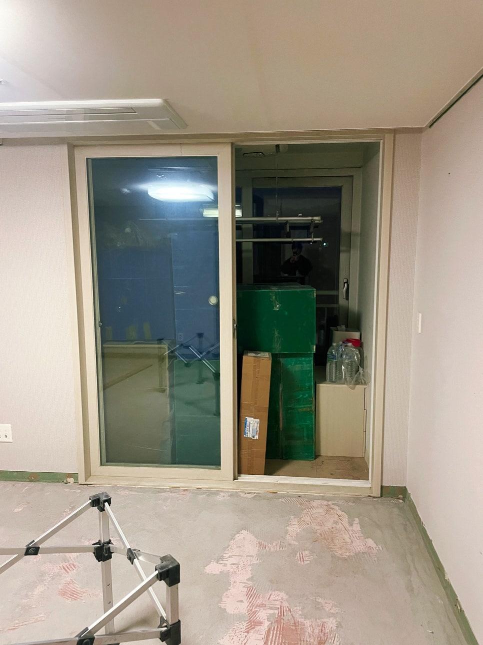 유리 슬라이딩 도어가 설치된 공사 중인 실내 공간